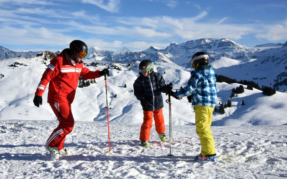Skilehrer der Schweizer Skischule unterrichtet zwei Kinder auf den Pisten von Rougemont