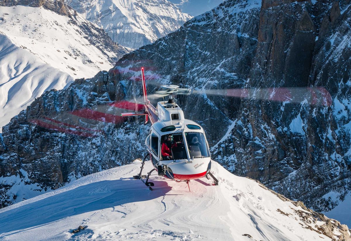 Swiss Helicopter landing on a snowy ridge above Gstaad