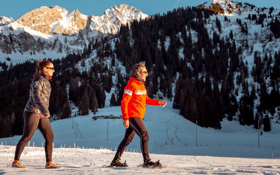 Privater Schneeschuhguide mit einer Gästin bei Sonnenuntergang in der Nähe von Rougemont